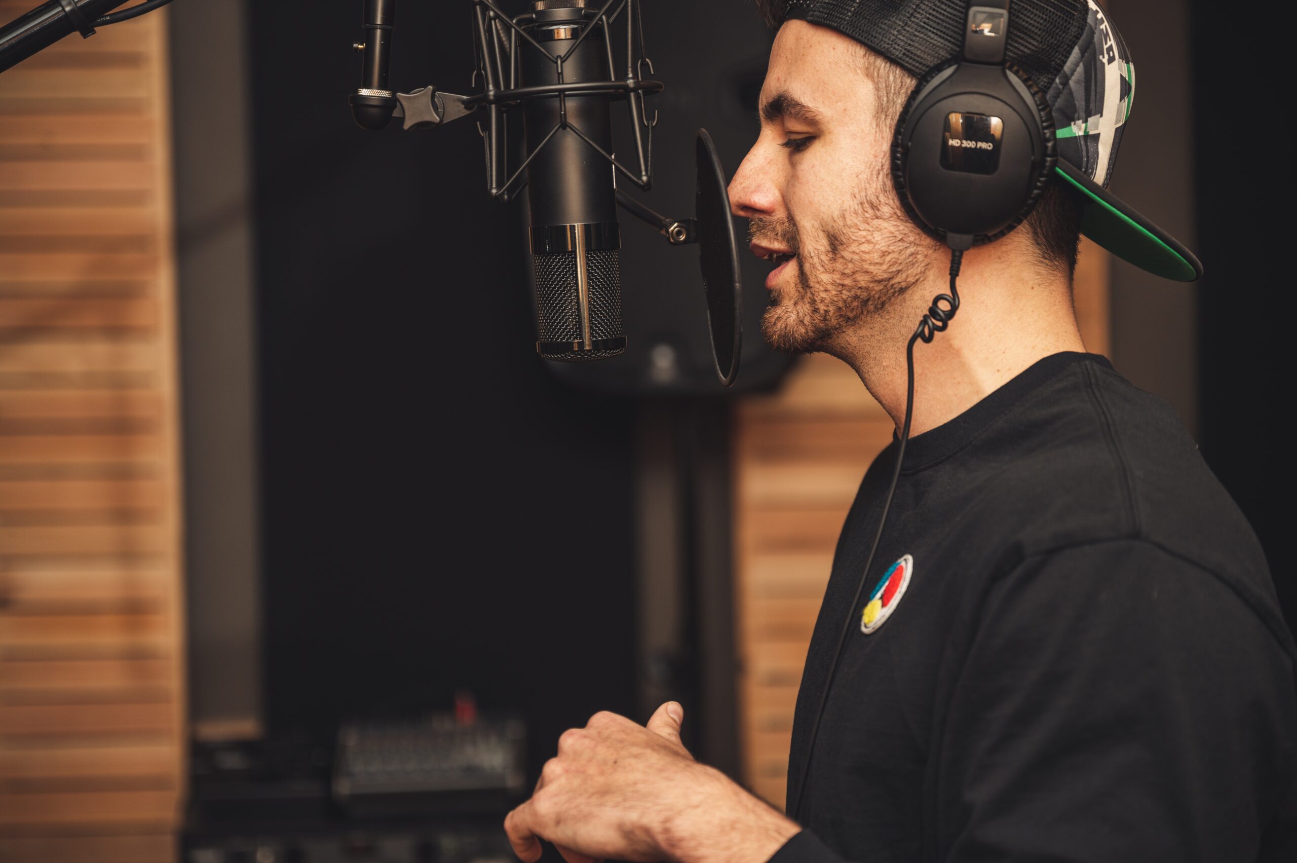 man talking into a microphone with a backwards hat